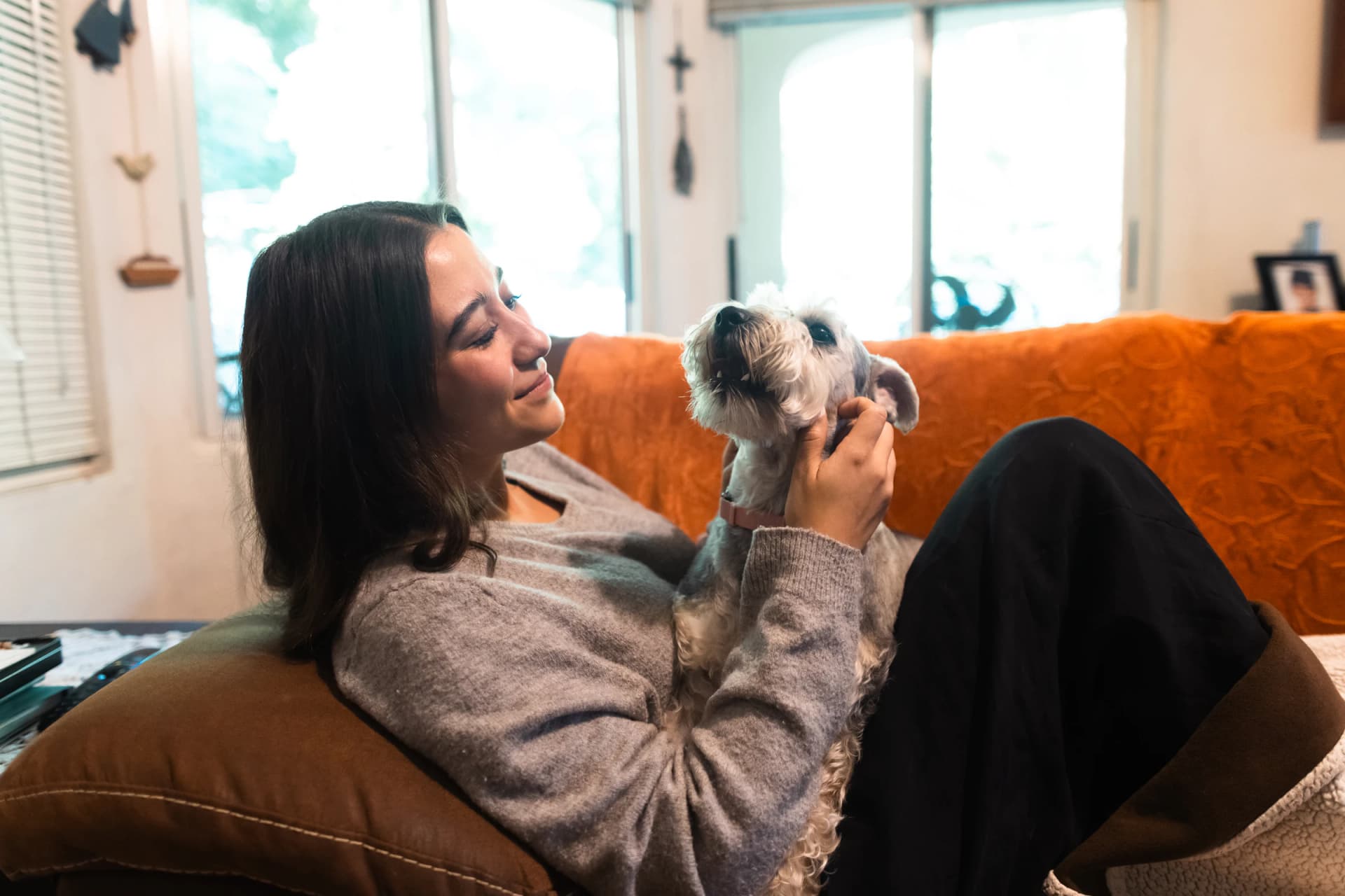 Joven acurrucada con su perro pequeño en el sofá